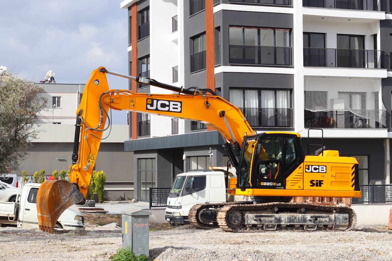 Services A yellow excavator operating at a city construction site in front of modern buildings.